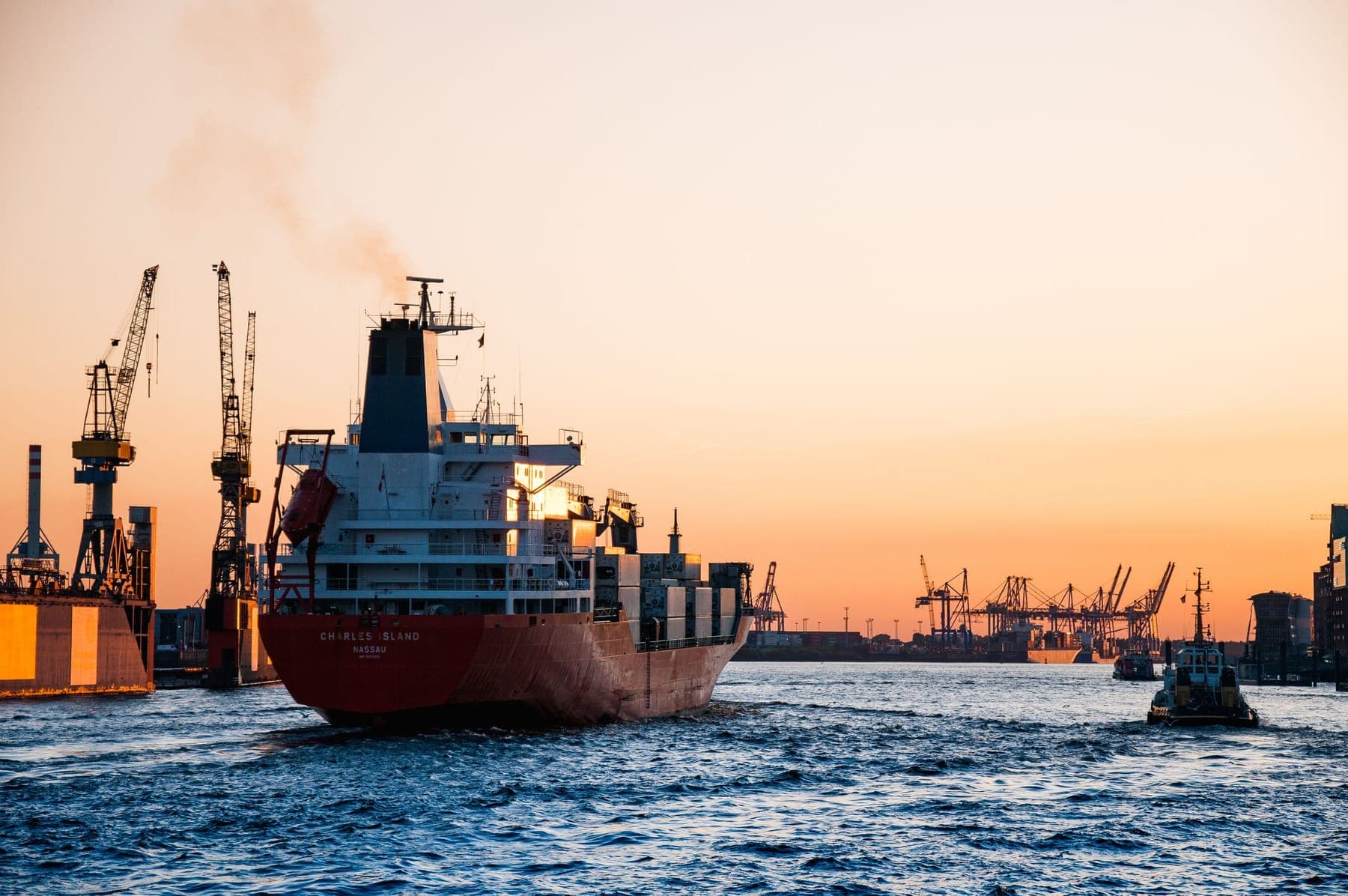 Navio de carga em porto com guindastes ao pôr do sol